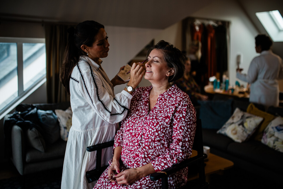 The mother of the bride has her makeup done, captured by a documentary photographer