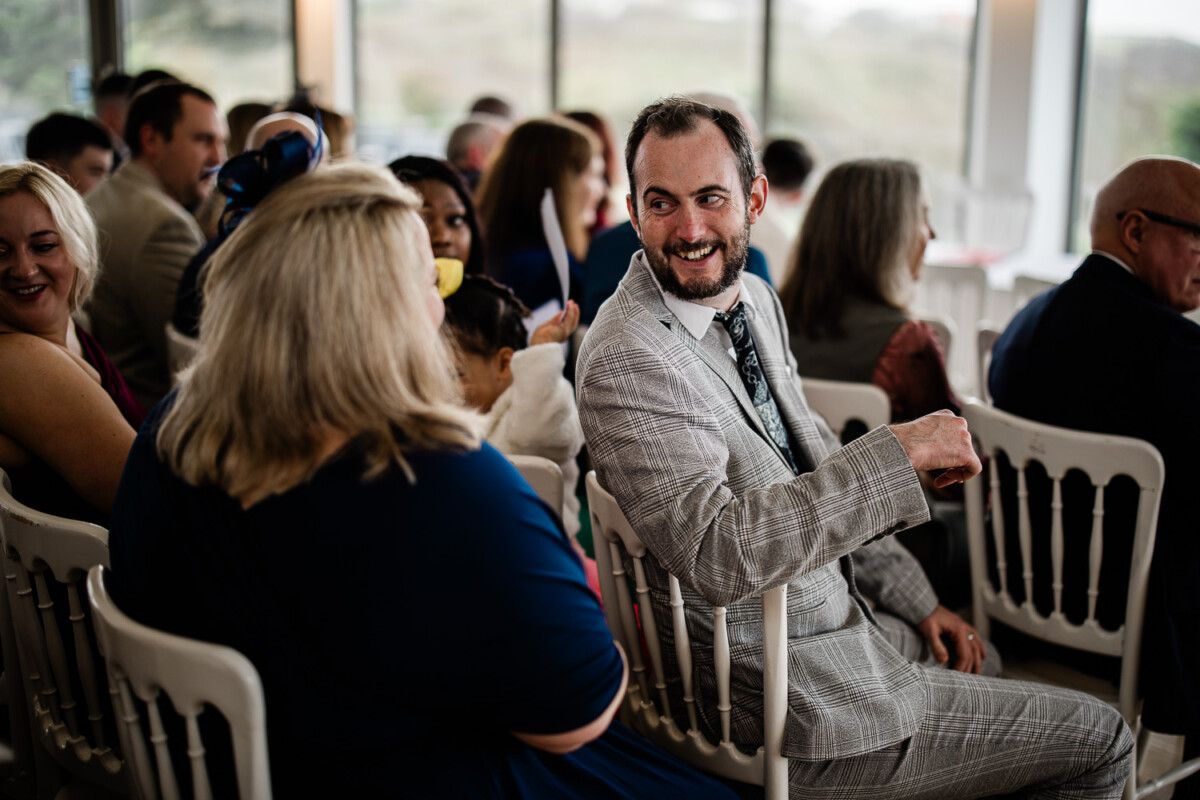 A natural wedding photography capture of wedding guests chatting before the ceremony begins