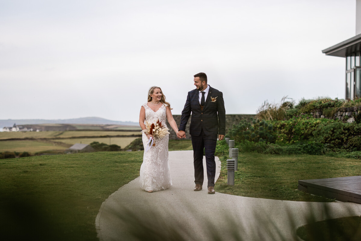 A bride and groom walk together during a polurrian on the lizard wedding in Cornwall