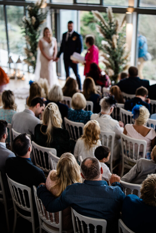 A candid moment of a couple embracing as they watch a bride and groom say their vows
