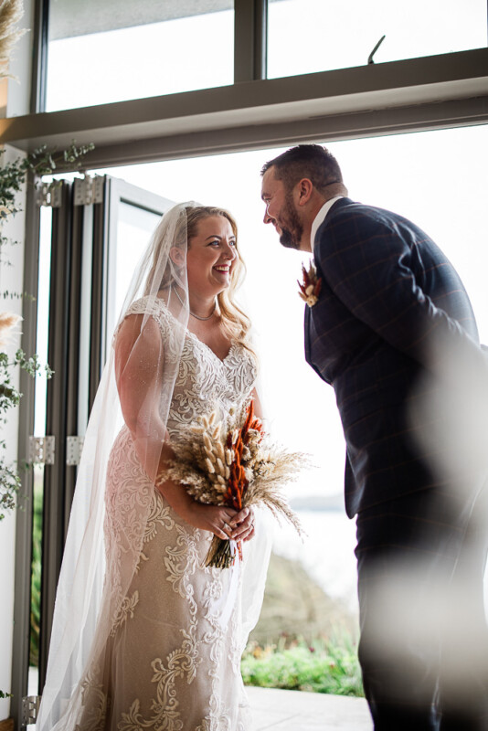 A candid moment as a bride and groom smile at each other while saying their vows