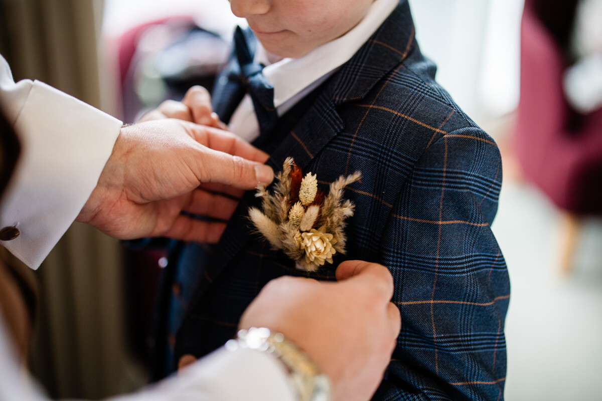 A rustic, dried flower boutonniere is attached