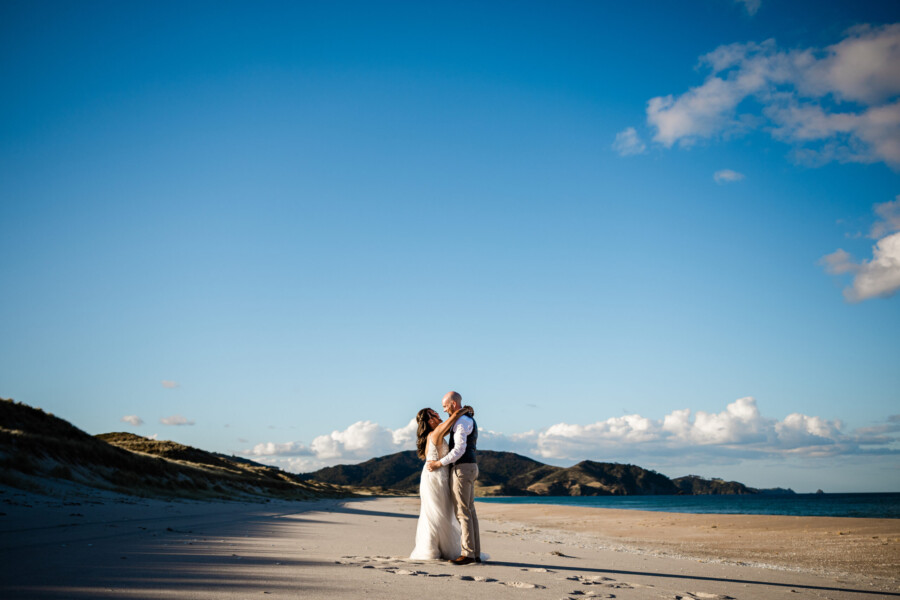 A bride and groom take a quiet moment on the beach, captured by a destination wedding NZ