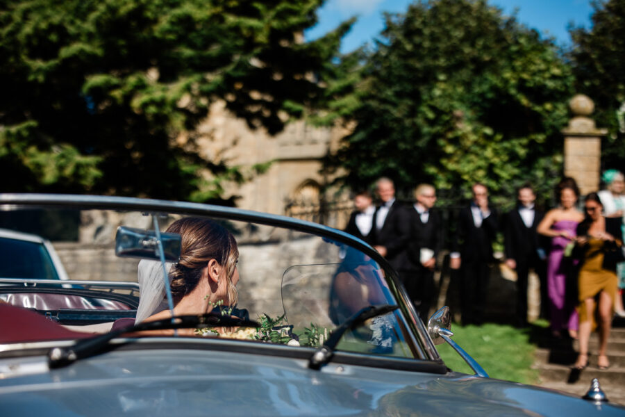 A bride in a vintage car in Chipping Norton, taken by a documentary style wedding photographer