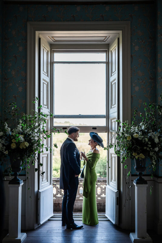 A candid moment between guests during a stately home wedding