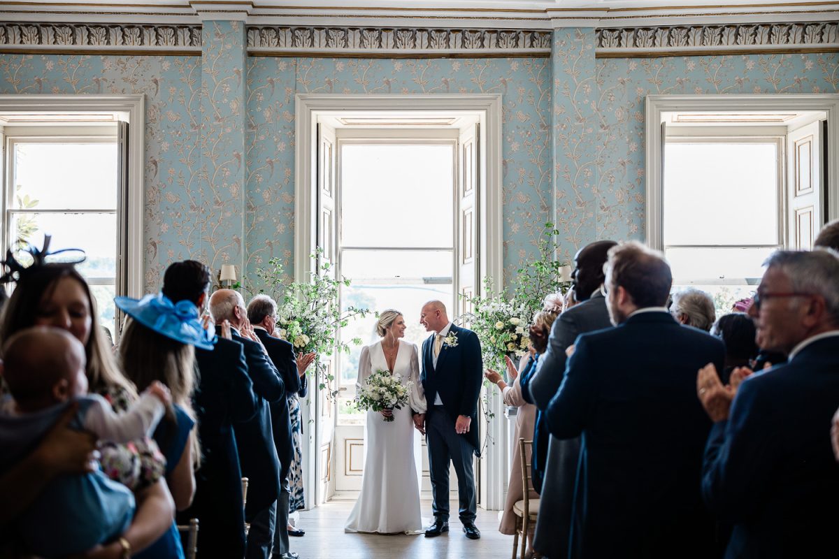 the bride and groom walk down the aisle during a country house wedding
