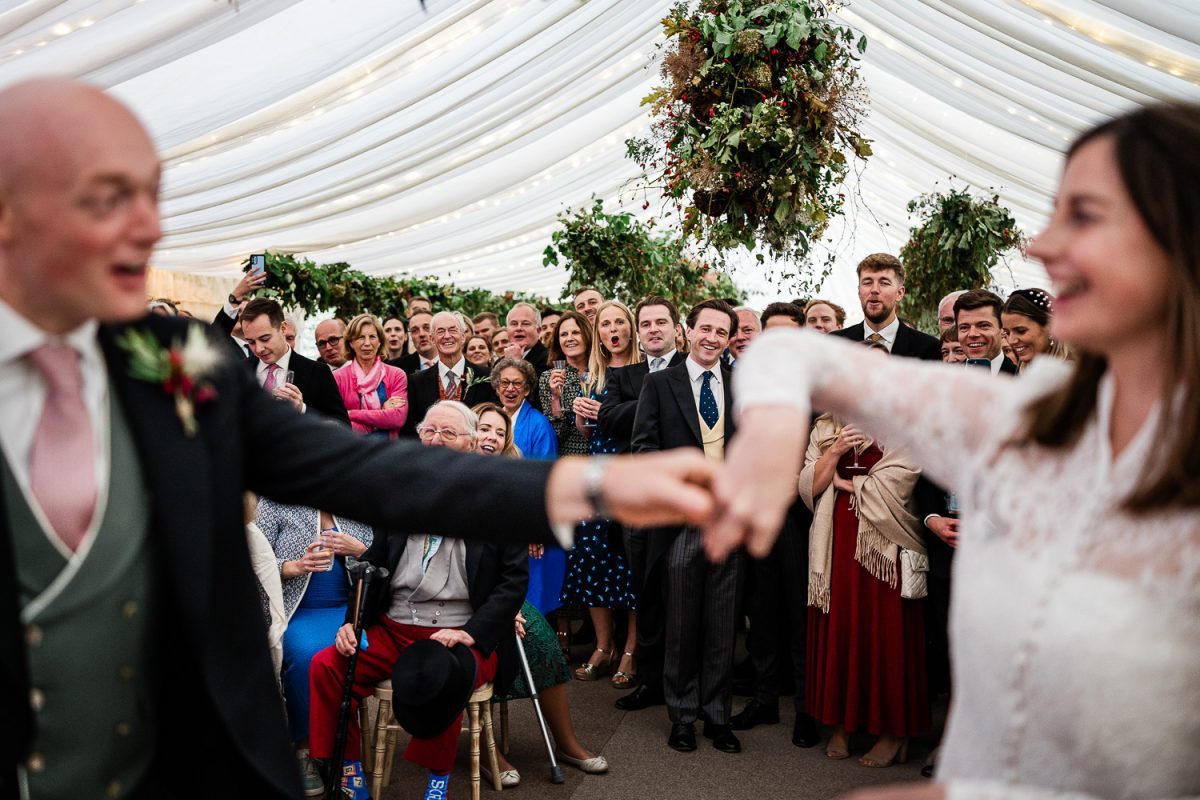 Guests watch as the bride and groom dance together during their marquee wedding
